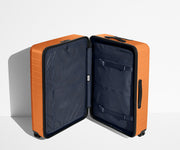The Large suitcase in Sorbet Orange shown open in an upright position to show interior organization and compression system