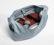 Large Featherlight Crossbody packed with clothes, a laptop, notebook, water bottle, headphones, and sunglasses