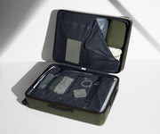 The Large suitcase in Olive Green shown open on its side and packed with Away's packing organizers to show capacity and the interior compression system, designed to help you pack more in