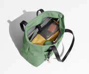 Tote bag packed with a laptop, water bottle, travel pouch, and sweater. A key is attached to the hidden key leash