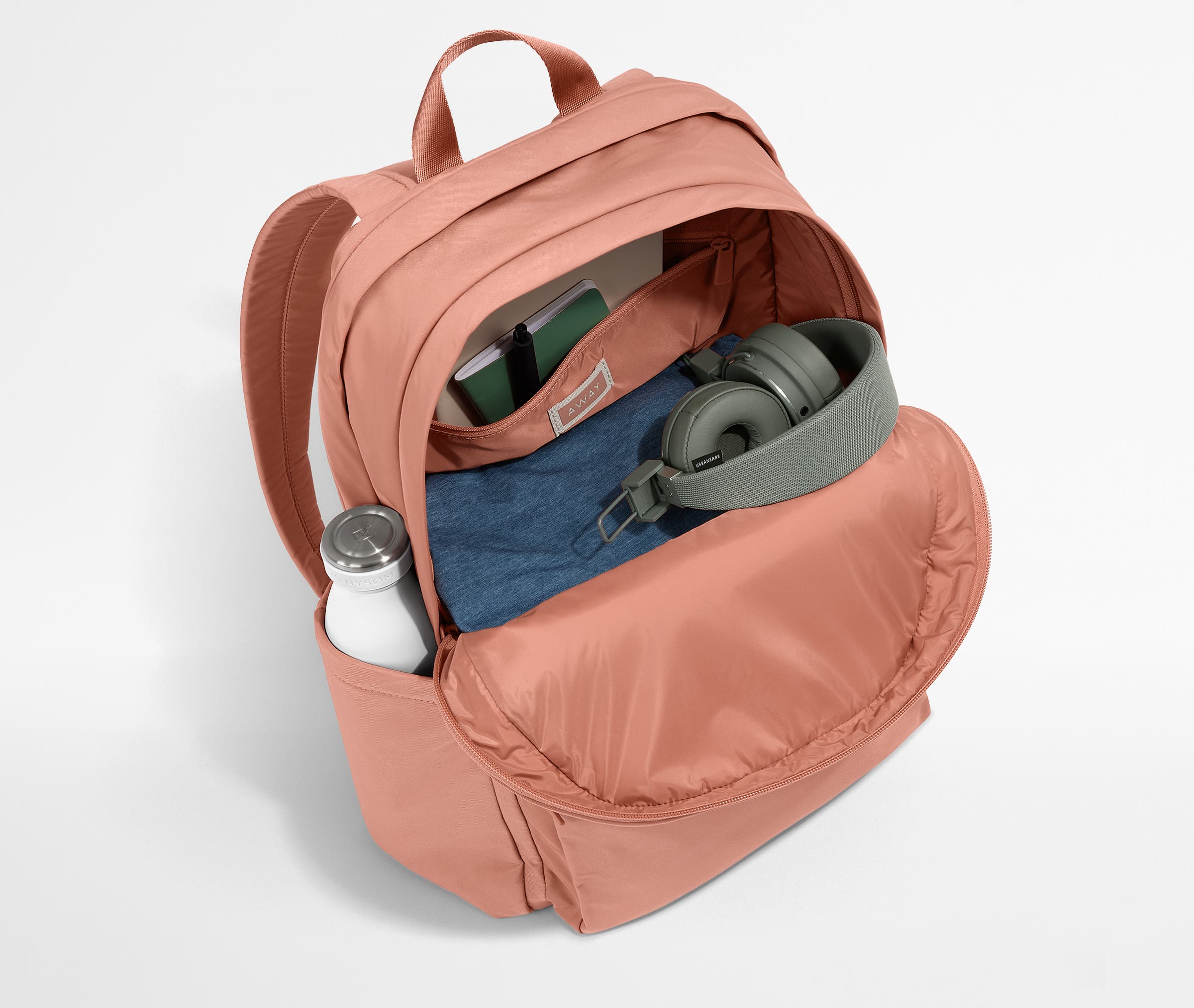 Front compartment packed with a notebooks, headphones, and clothing