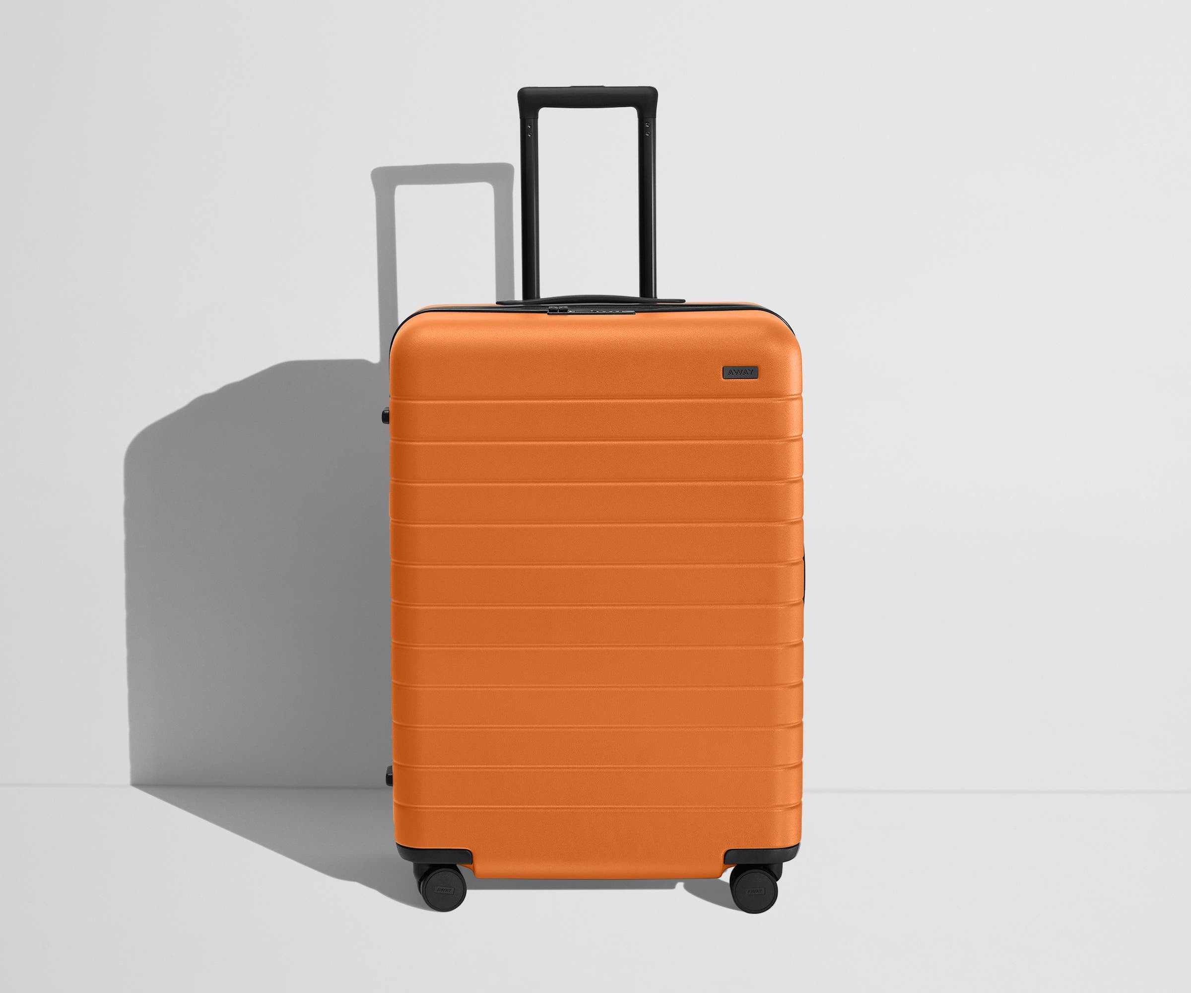 Front product view of The Medium Flex suitcase in Sorbet Orange with raised handle