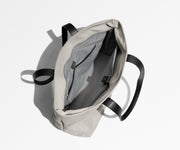 Unzipped and unpacked Everywhere Tote bag, showing the interior zip pockets, slip pockets, and laptop pocket