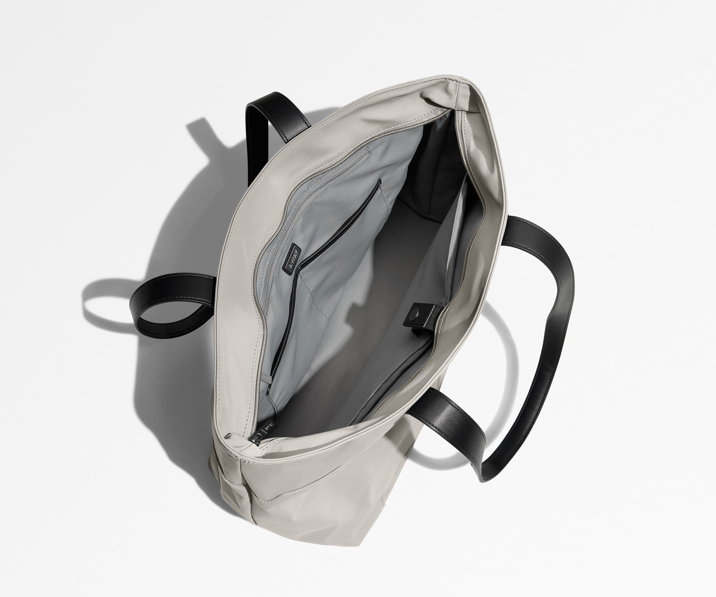 Unzipped and unpacked Everywhere Tote bag, showing the interior zip pockets, slip pockets, and laptop pocket