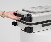 The Front Pocket Carry-On suitcase in Cloud Gray shown from below highlighting the underside grab handle