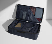 The Trunk suitcase in Navy Blue shown open on its side and packed with Away's packing organizers to show capacity and the interior compression system, designed to help you pack more in