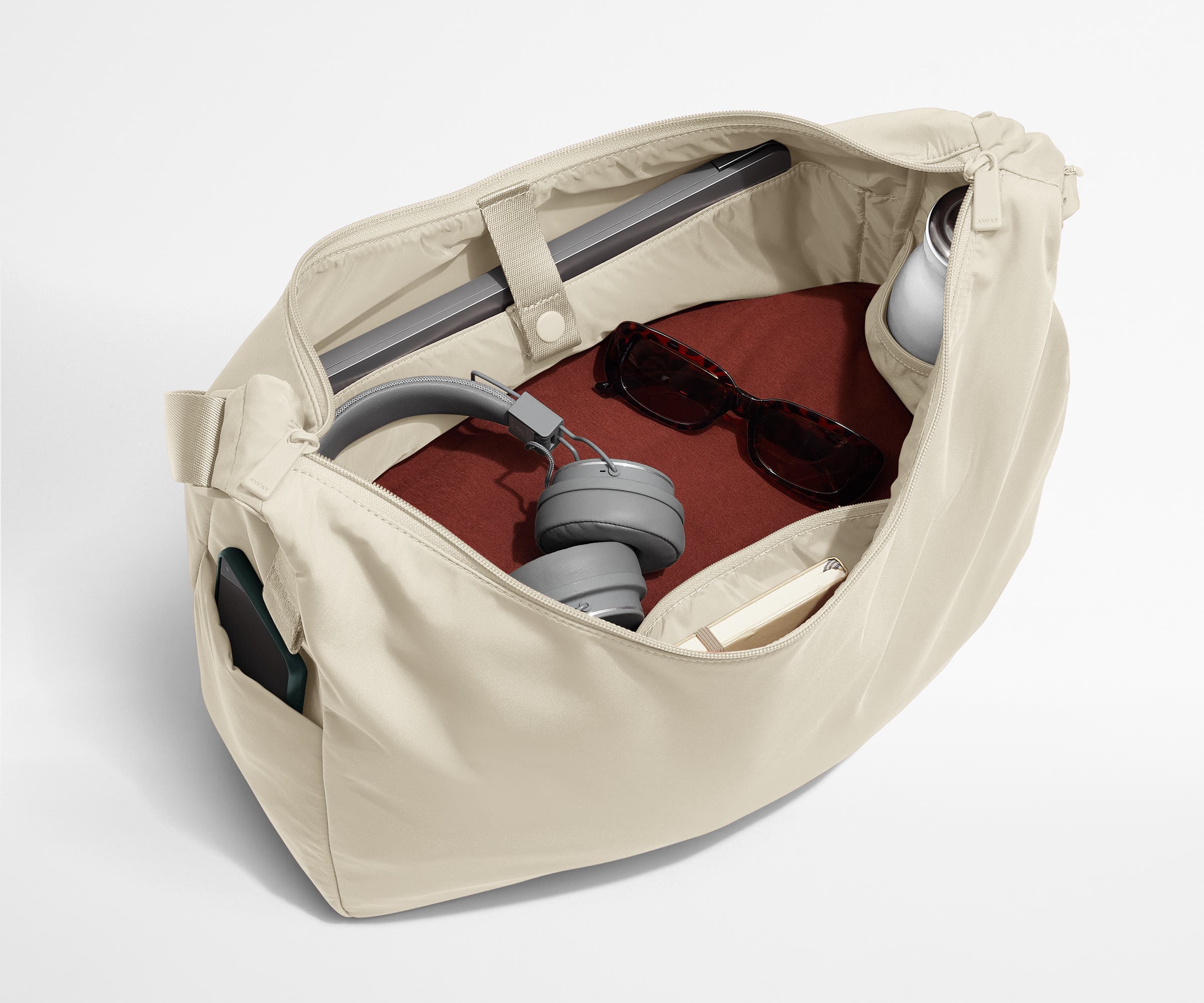 Large Featherlight Crossbody packed with clothes, a laptop, notebook, water bottle, headphones, and sunglasses