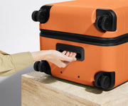 The Trunk suitcase in Sorbet Orange shown from below highlighting the underside grab handle