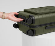 The Front Pocket Carry-On suitcase in Olive Green shown from below highlighting the underside grab handle