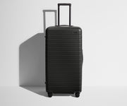 Front product view of The Trunk suitcase in Jet Black with raised handle