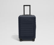 Front product view of The Front Pocket Bigger Carry-On suitcase in Navy Blue with raised handle