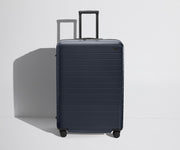 Front product view of The Large Flex suitcase in Navy Blue with raised handle