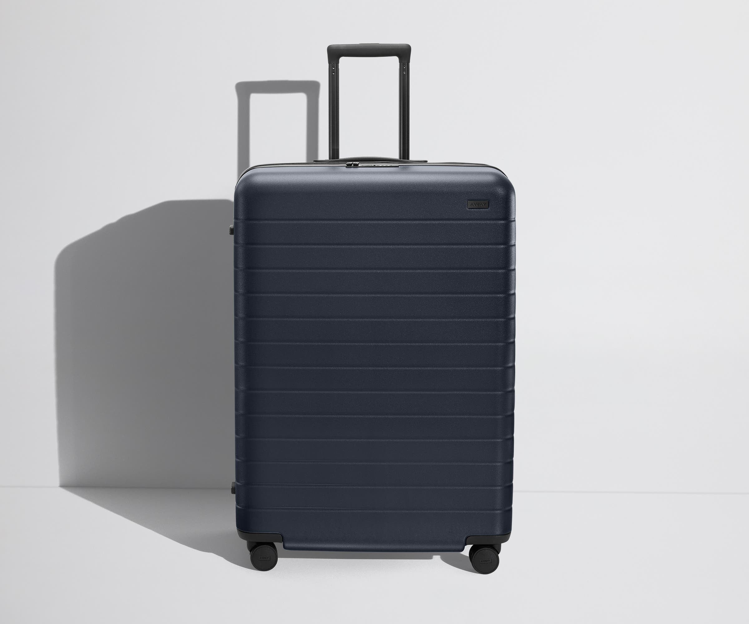 Front product view of The Large Flex suitcase in Navy Blue with raised handle