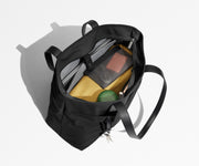 Tote bag packed with a laptop, water bottle, travel pouch, and sweater. A key is attached to the hidden key leash