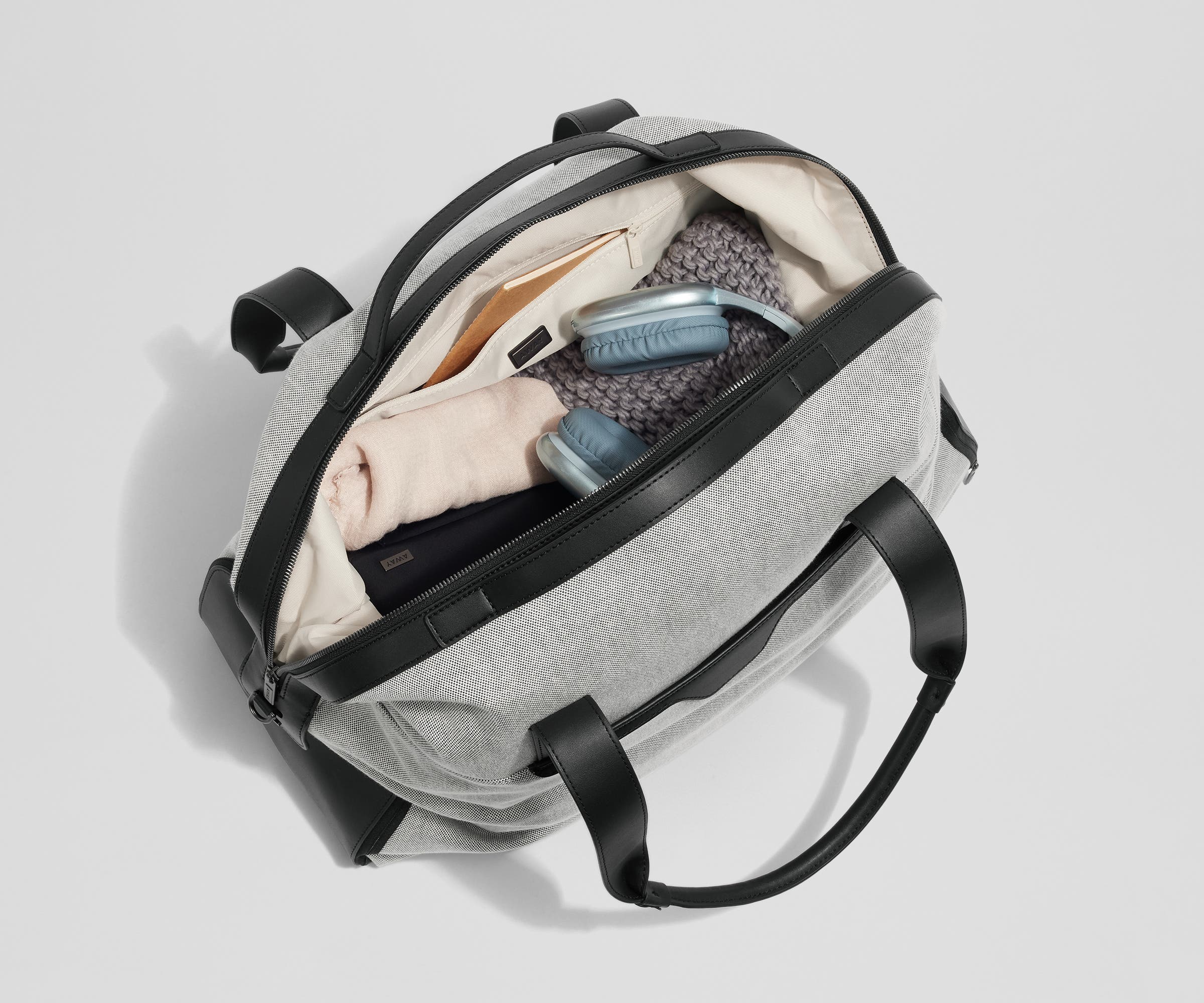Top-down view of the weekender packed with clothing, headphones, a toiletry bag, and notebook