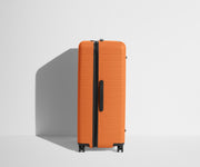 Side product view of The Trunk suitcase in Sorbet Orange to show the slimmer top lid and deeper main compartment for easy access and packing