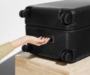The Trunk suitcase in Jet Black shown from below highlighting the underside grab handle