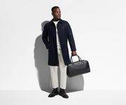 Person holding the Transit Leather Duffle by its top handles