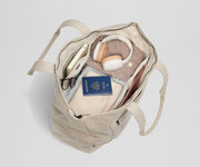 Top-down view of the tote packed with clothing, passport, headphones, a notebook, and a laptop among other travel essentials