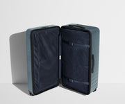 The Trunk suitcase in Coast Blue shown open in an upright position to show interior organization and compression system