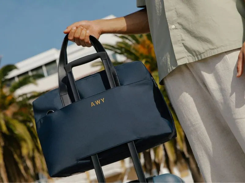 A navy Away duffle with three letters embroidered on the back