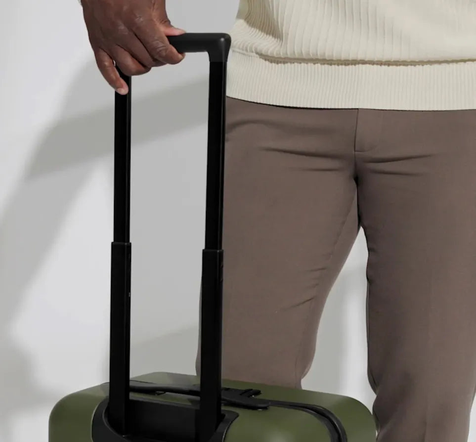 A close shot of a man pulling up the handle on an Away suitcase