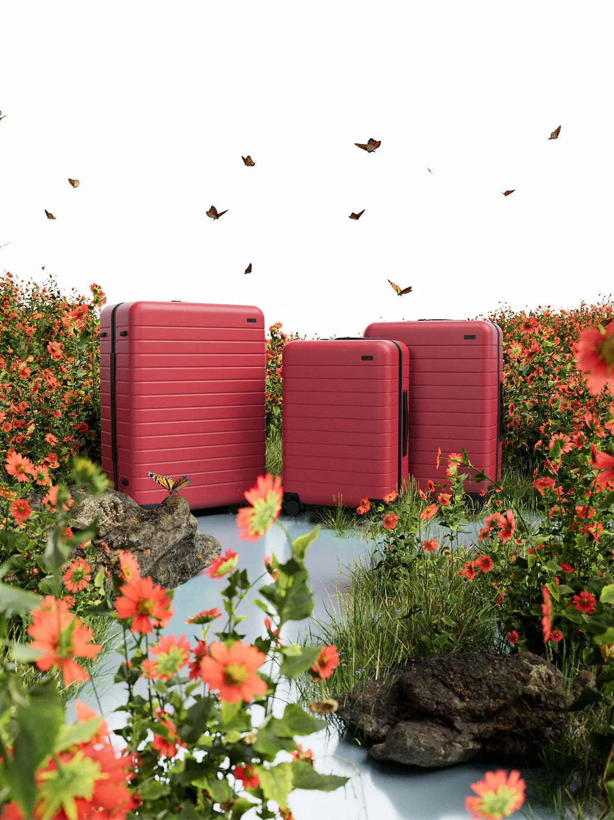 A set of three Away suitcases in red amongst a surreal background of red flowers, rocks, and monarch butterflies