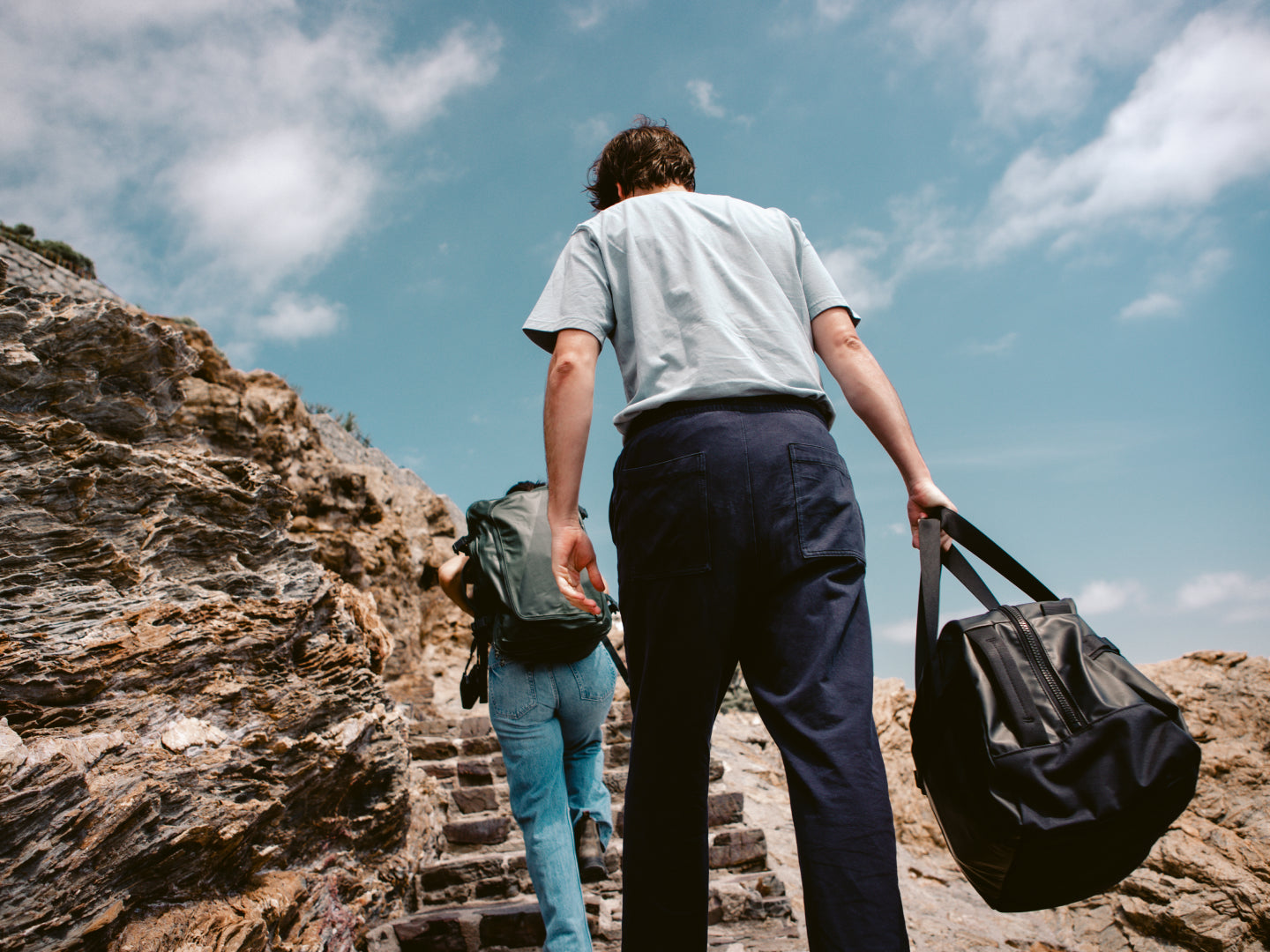 Two people walking up stone steps in nature with the Away Active Duffle and Active Convertible Backpack
