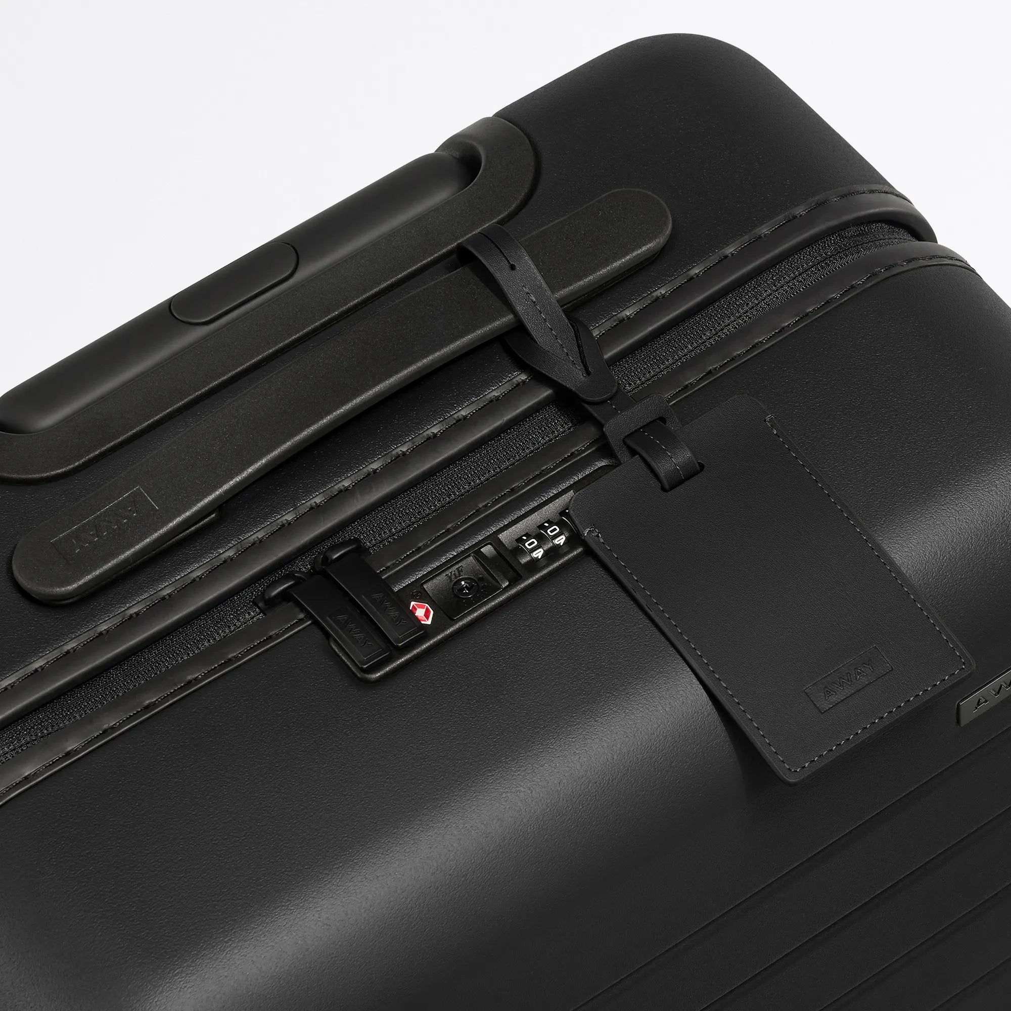 A close up view of the top lock on an Away suitcase in black