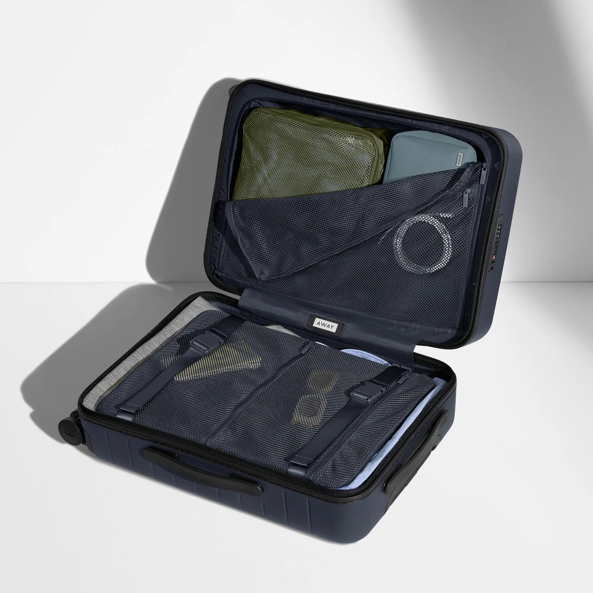An open Away suitcase packed using Away packing cubes and other accessories