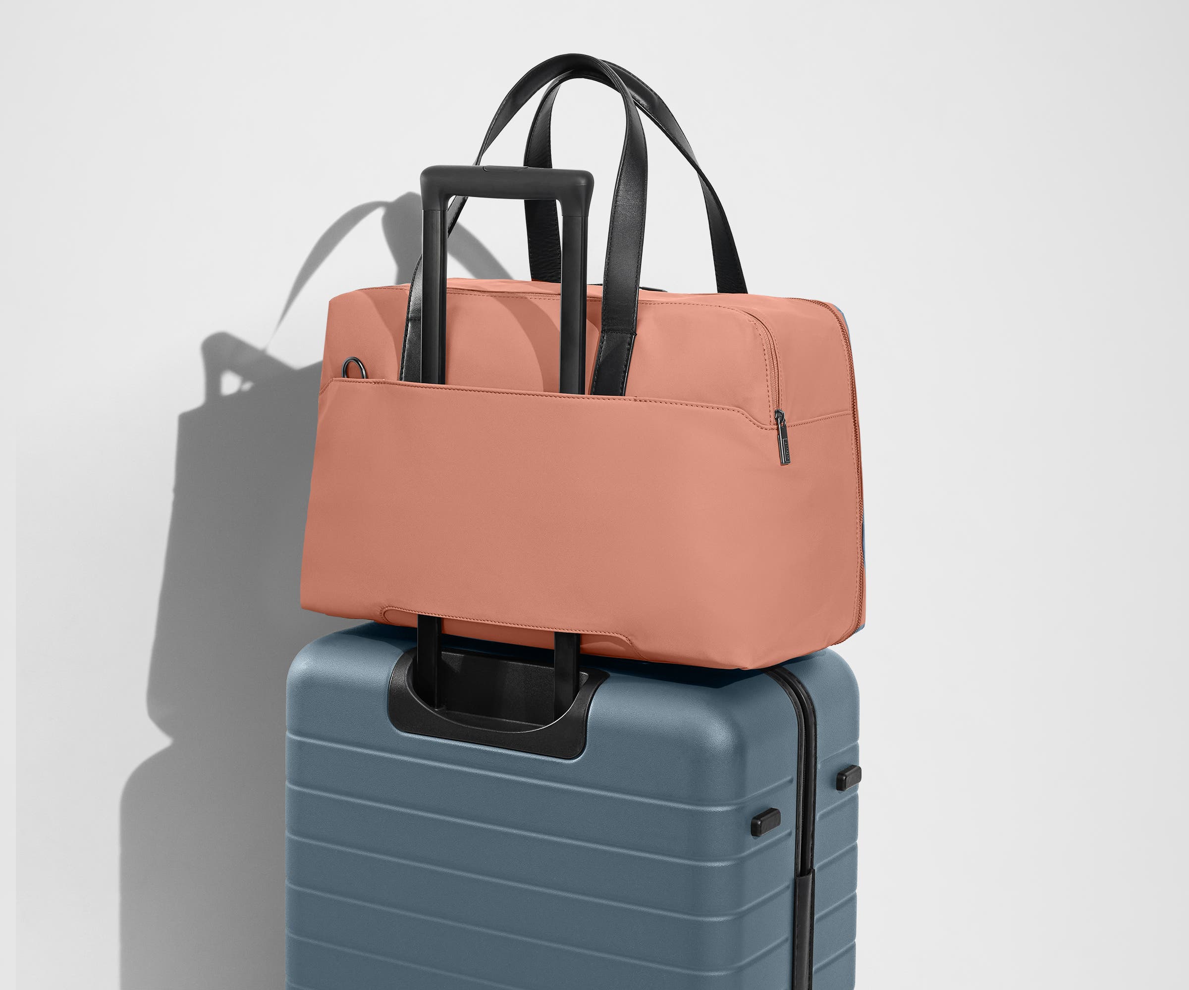 The Overnight Bag secured to an Away checked suitcase using the trolley sleeve