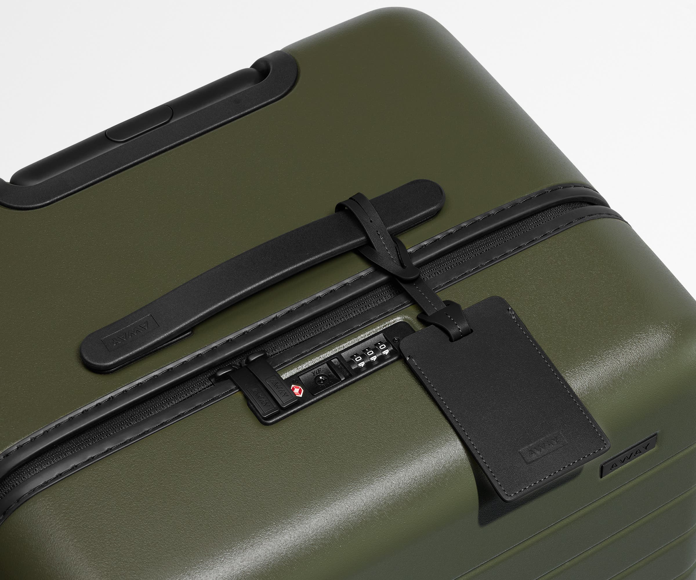 The Trunk suitcase in Olive Green shown shown from above highlighting TSA-approved combination lock and recycled leather luggage tag