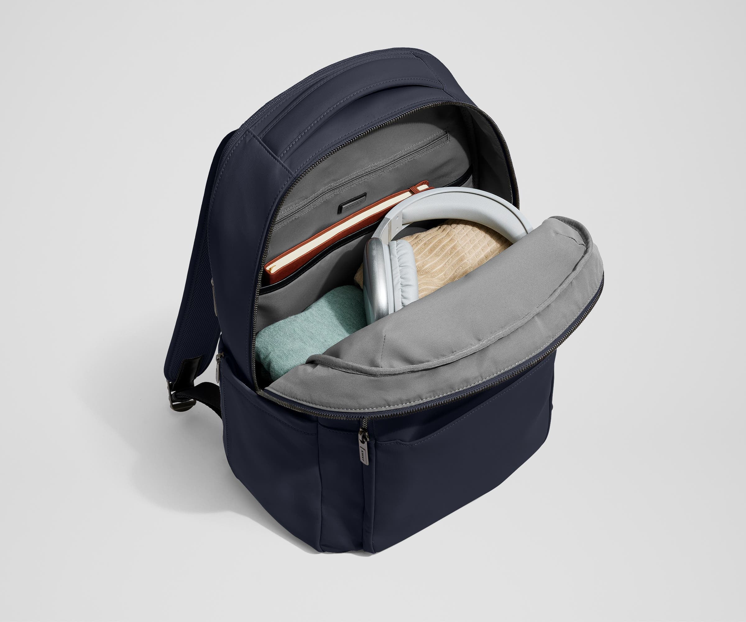 Main compartment of the Commuter Backpack packed with a notebook, light layers, and headphones