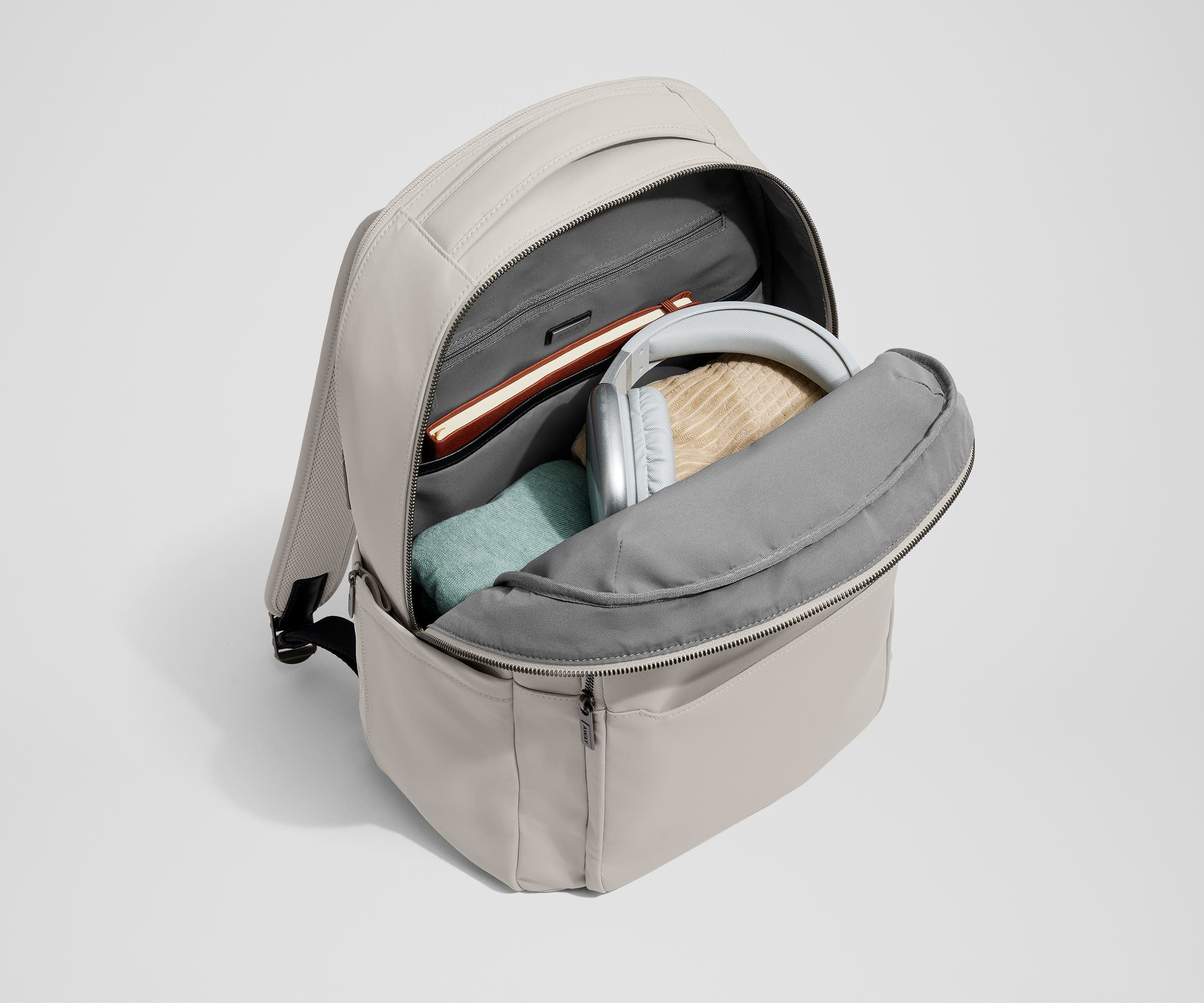 Main compartment of the Commuter Backpack packed with a notebook, light layers, and headphones