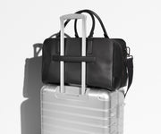 Transit Leather Duffle featured with a removable shoulder strap on top of an Aluminum suitcase