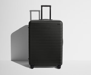 Front product view of The Large suitcase in Jet Black with raised handle