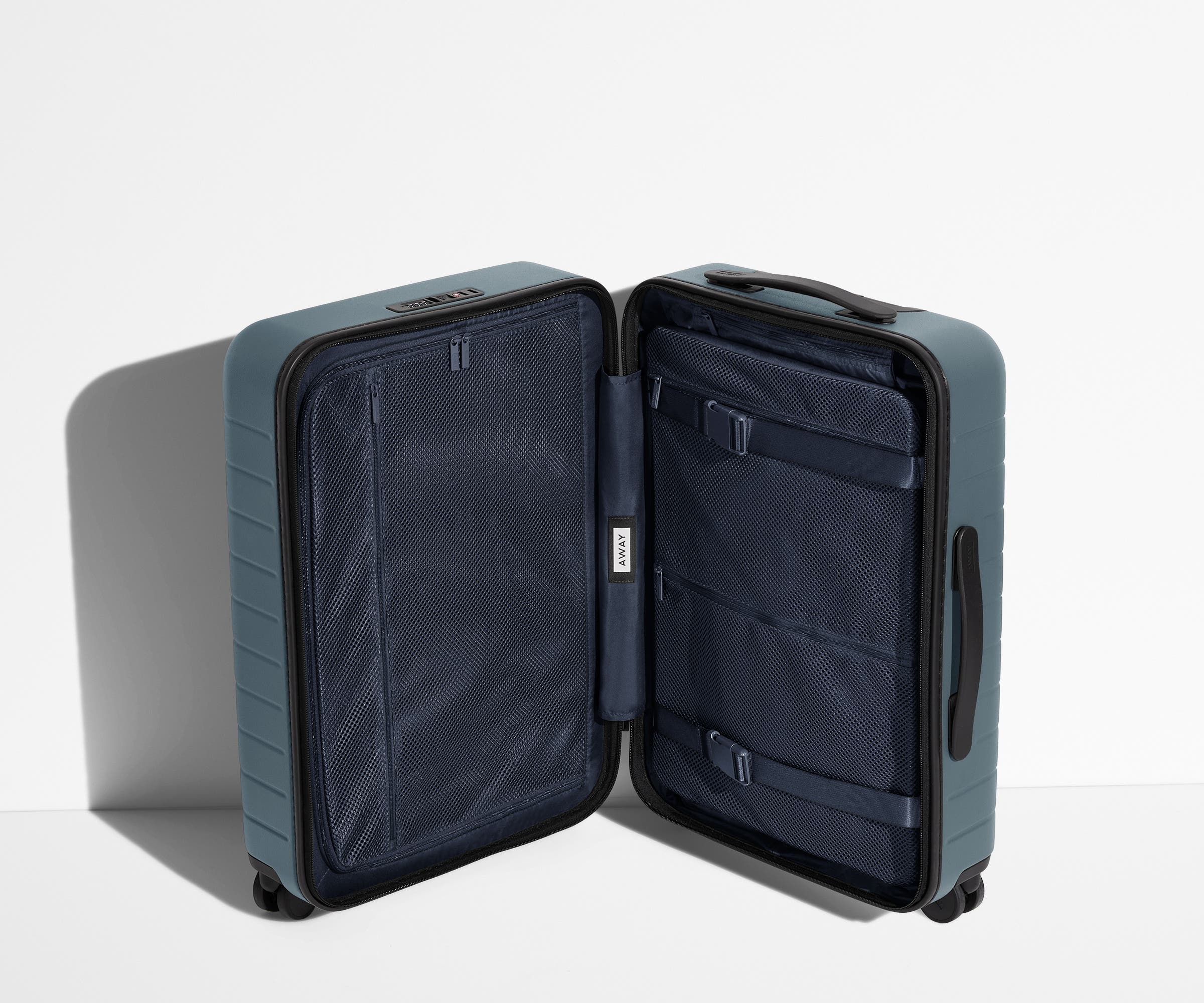 The Bigger Carry-On suitcase in Coast Blue shown open in an upright position to show interior organization and compression system