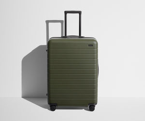 Front product view of The Medium suitcase in Olive Green with raised handle