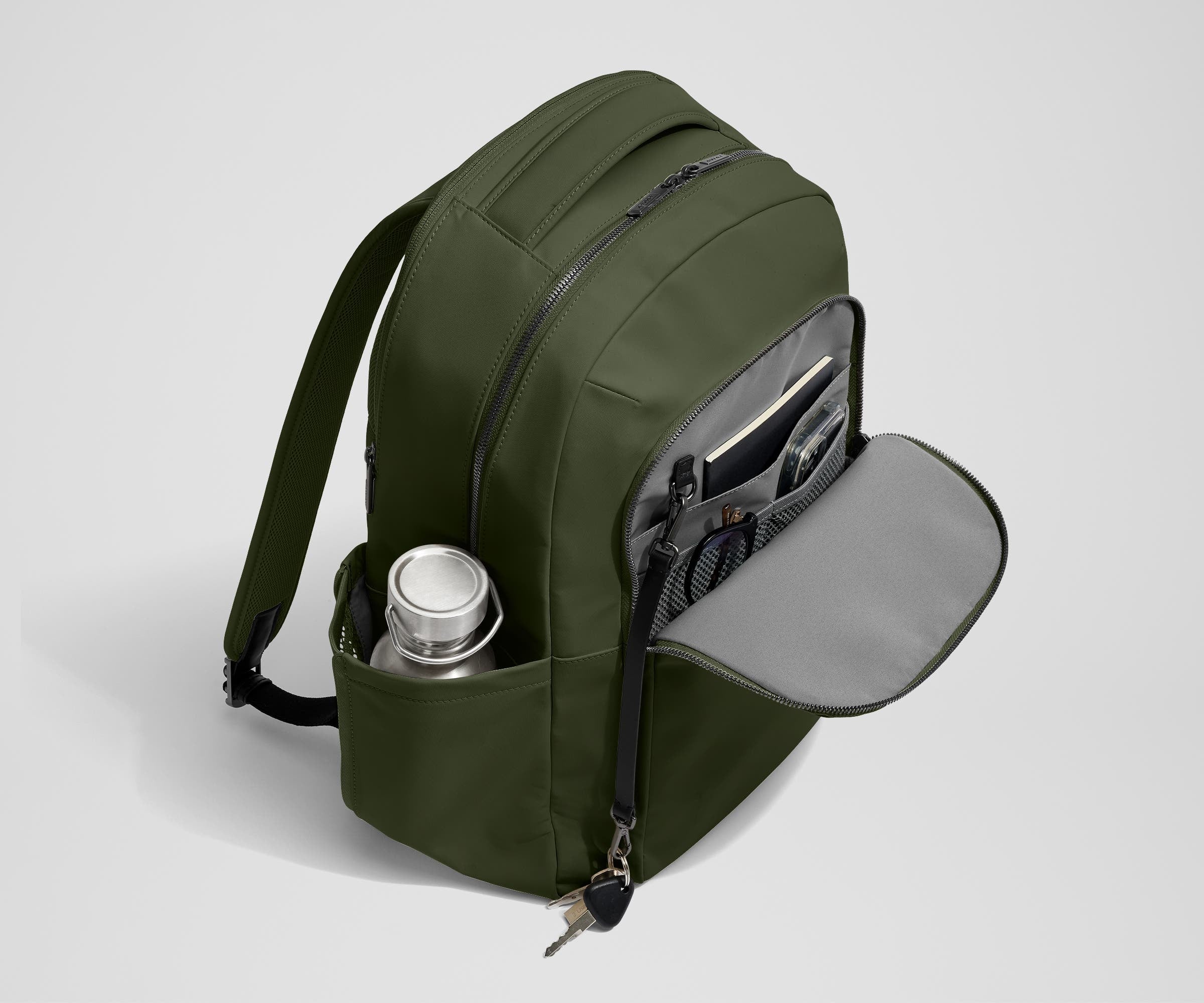 Front exterior zip pocket, detachable key clip, and exterior water bottle pocket of The Commuter Backpack