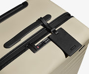 The Trunk suitcase in Salt White (Gloss) shown shown from above highlighting TSA-approved combination lock and recycled leather luggage tag
