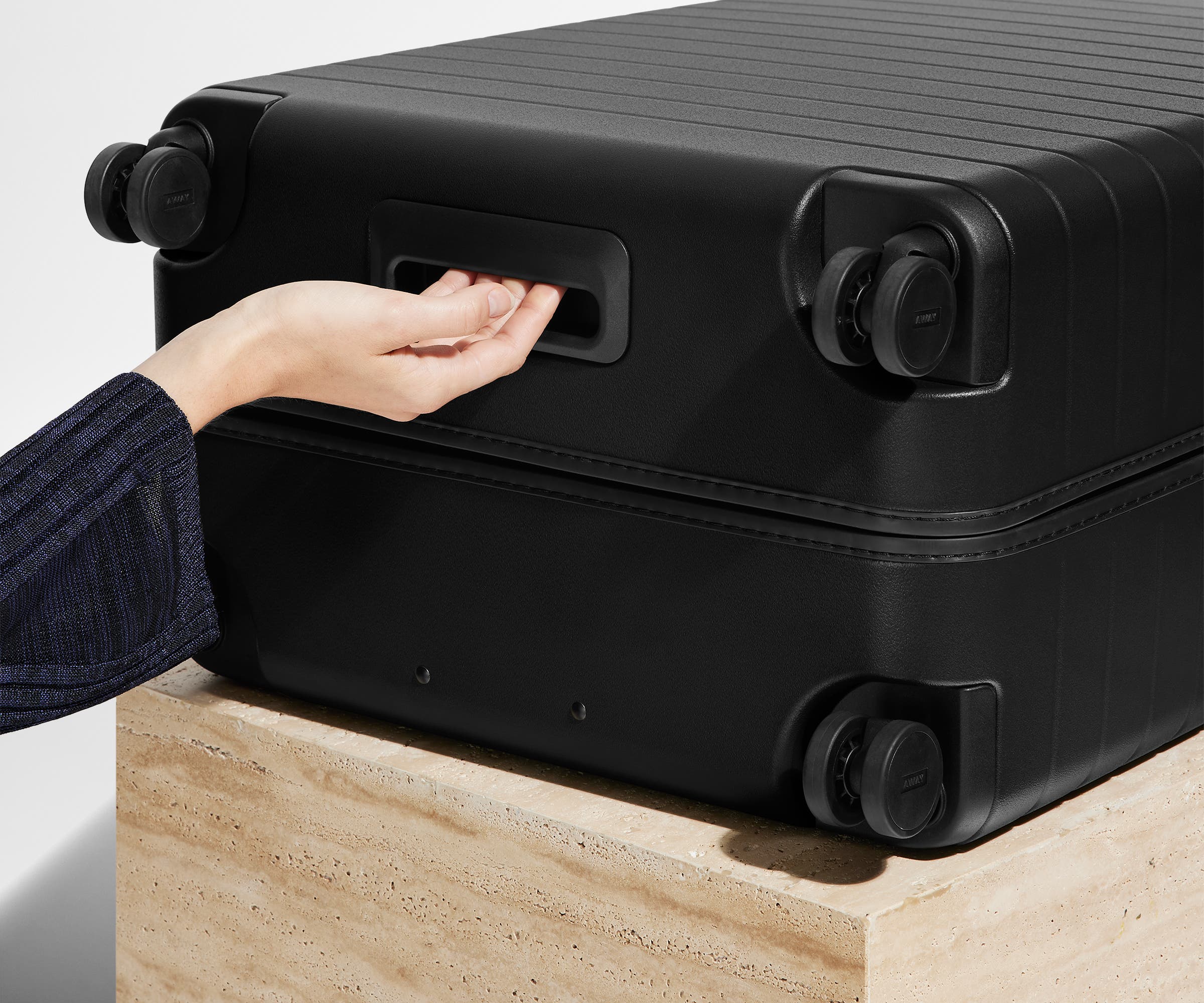 The Large suitcase in Jet Black shown from below highlighting the underside grab handle