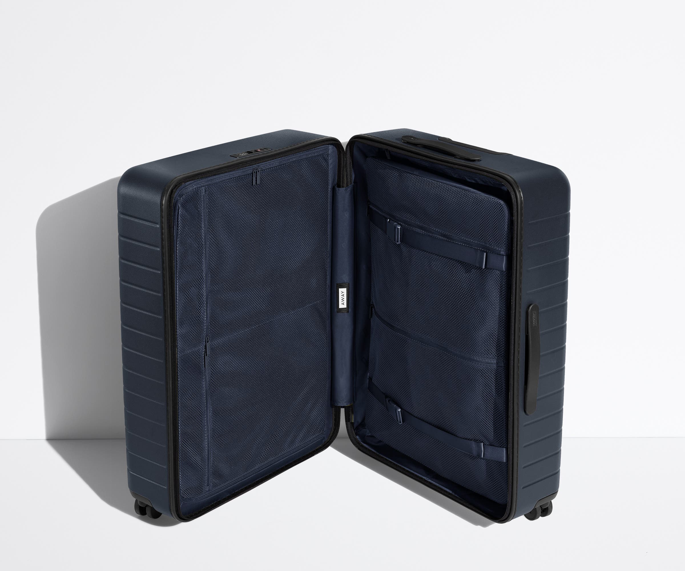 The Medium suitcase in Navy Blue shown open in an upright position to show interior organization and compression system