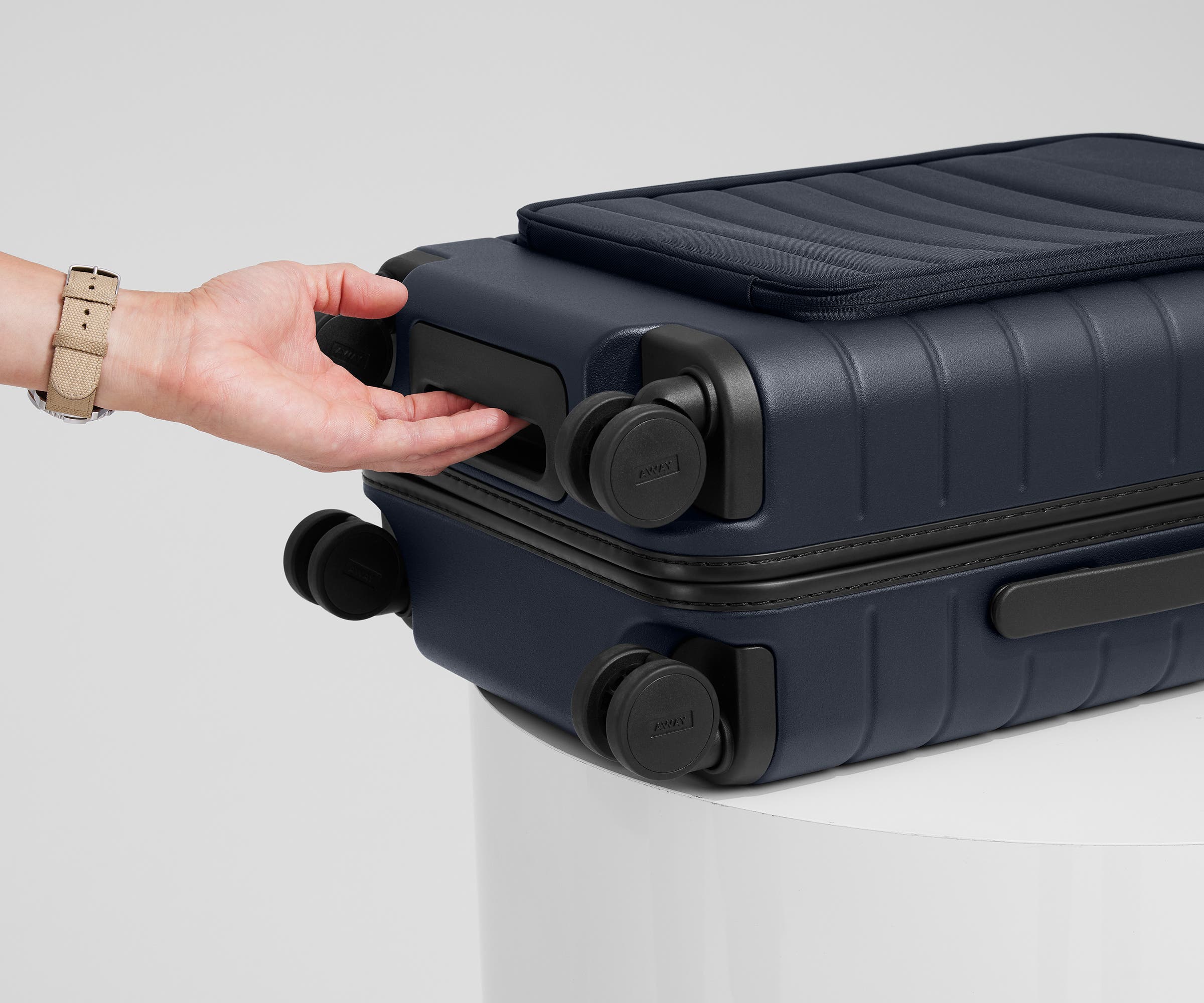 The Front Pocket Carry-On suitcase in Navy Blue shown from below highlighting the underside grab handle