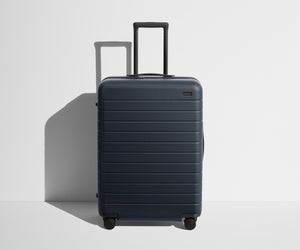 Front product view of The Medium suitcase in Navy Blue with raised handle
