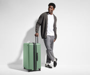 6'1" person walking with The Large Flex suitcase