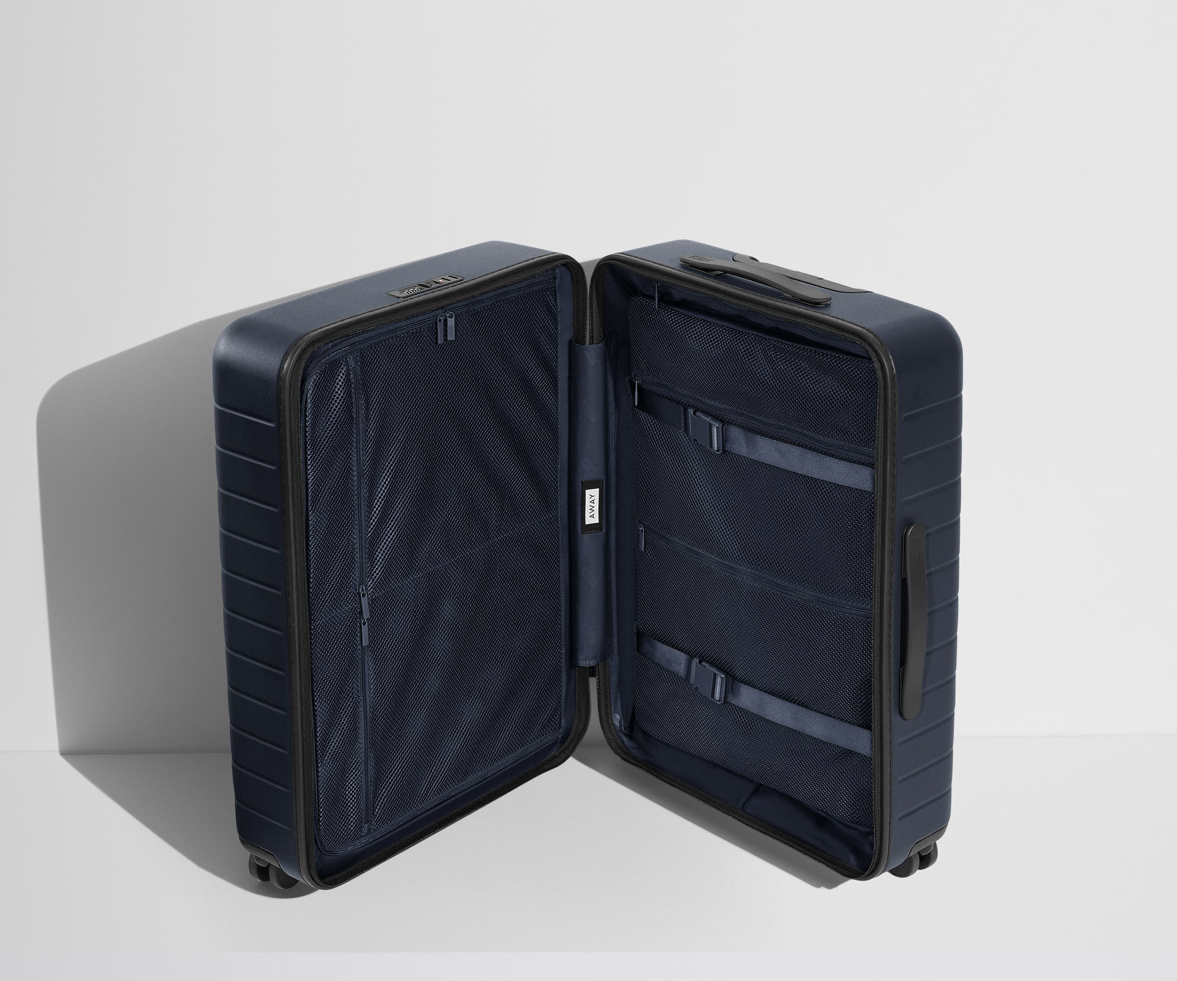 The Medium suitcase in Coast Blue shown open in an upright position to show interior organization and compression system