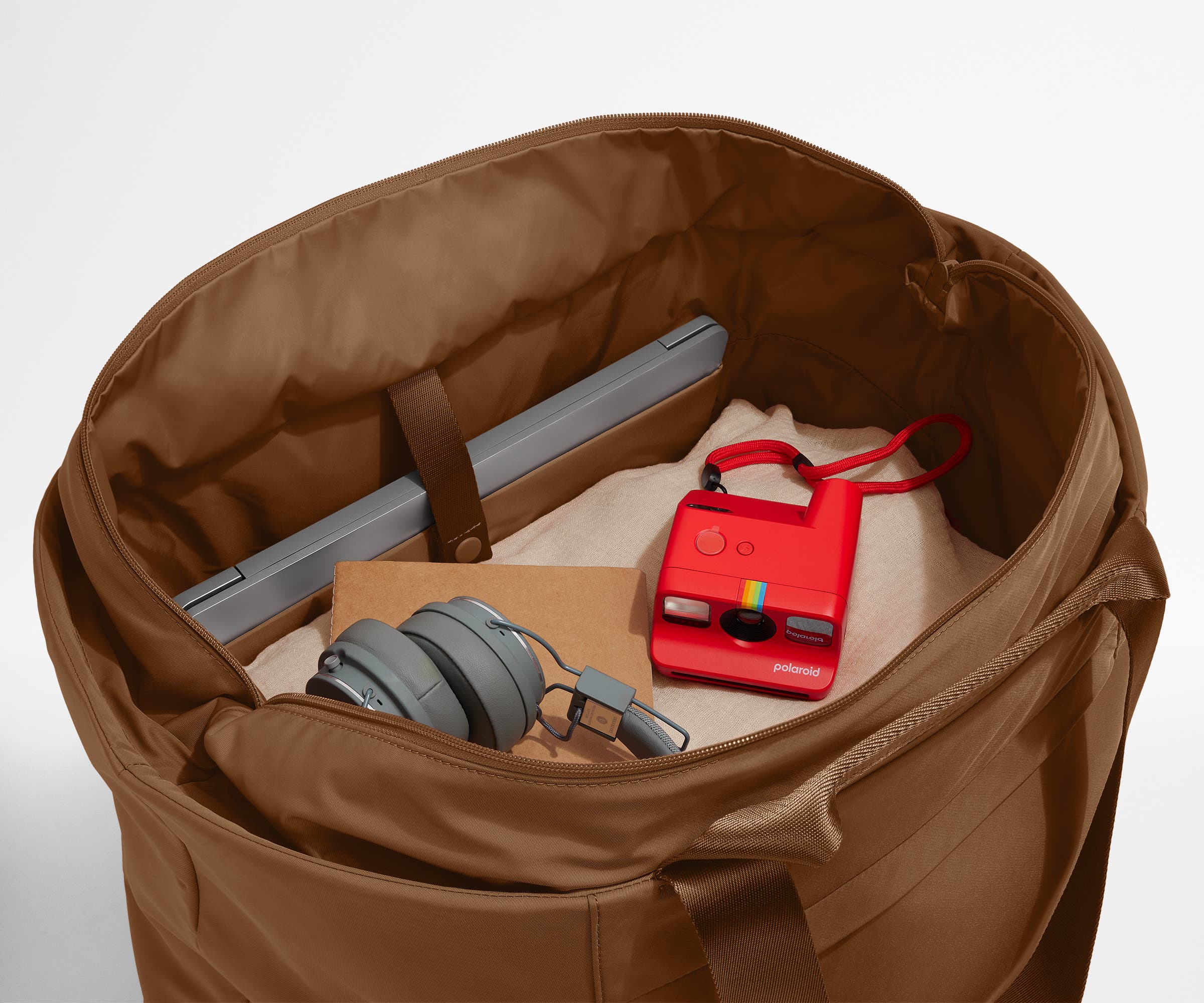 Interior packed with clothing, a laptop, headphones, notebook, and camera