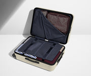 The Medium suitcase in Salt White (Gloss) shown open on its side and packed with Away's packing organizers to show capacity and the interior compression system, designed to help you pack more in