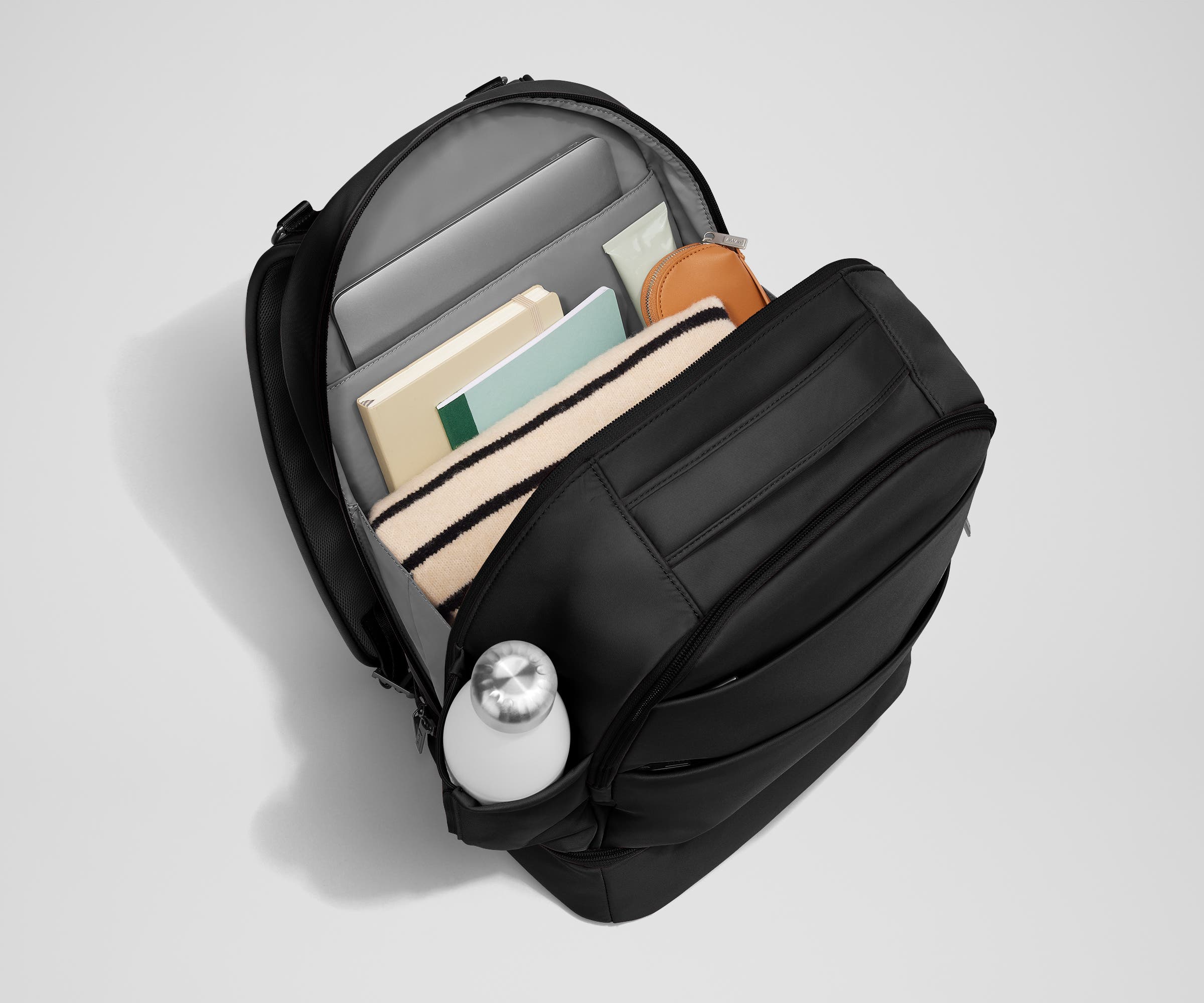 Back main compartment packed with adult travel essentials, including a laptop, notebook, and extra clothes