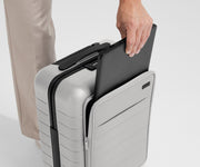 Zoomed in shot of talent slipping a laptop into the front pocket of The Front Pocket Carry-On in Cloud Gray